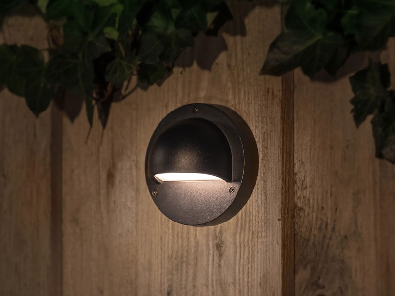 Wandleuchte Deimos an Holzzaun montiert